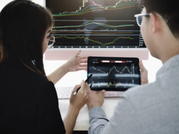 An investment expert points a pen at a tablet monitor to analyze the stock market to teach you how to make a profit.